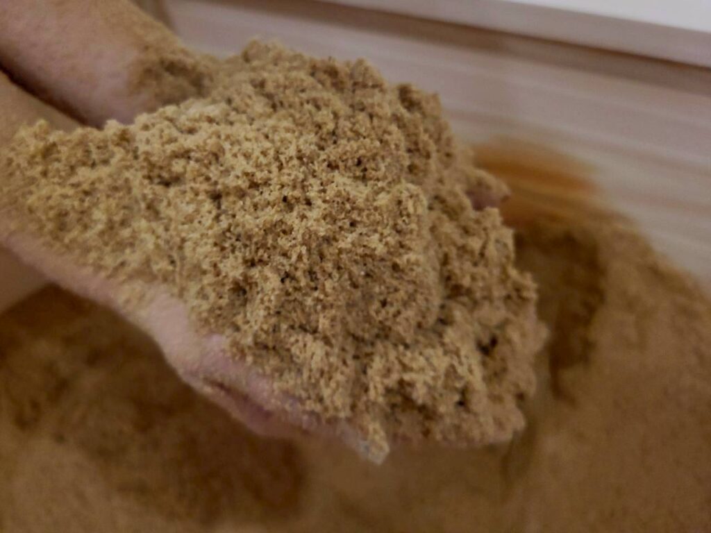 酵素浴の発酵床を手でならす作業